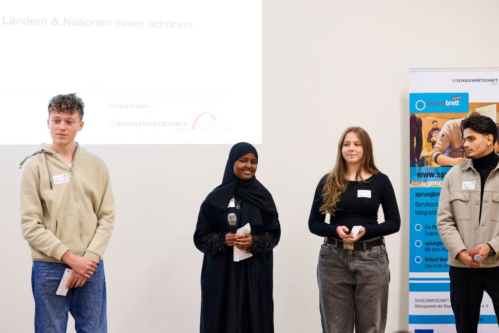 Schülerinnen und Schüler stehen vor einer Präsentation der Schulewirtschaft.