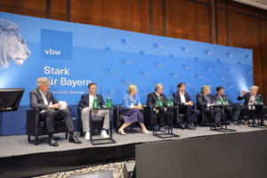 Acht Menschen sitzen bei dem Kongress auf der Bühne und besprechen sich.