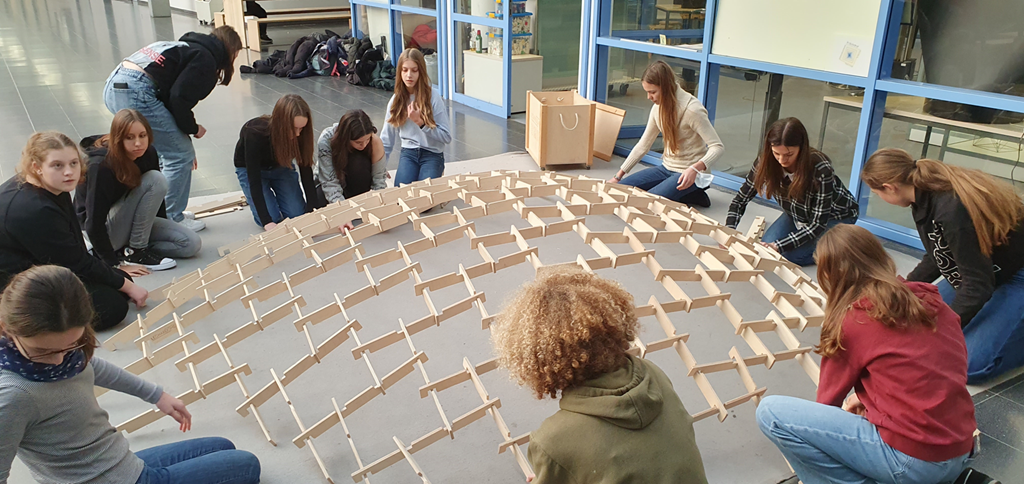 Schülerin bauen eine große Struktur aus Holz.