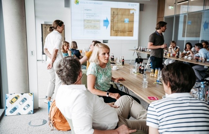 Gymnasiallehrkräfte beraten sich an einem langen Konferenztisch.