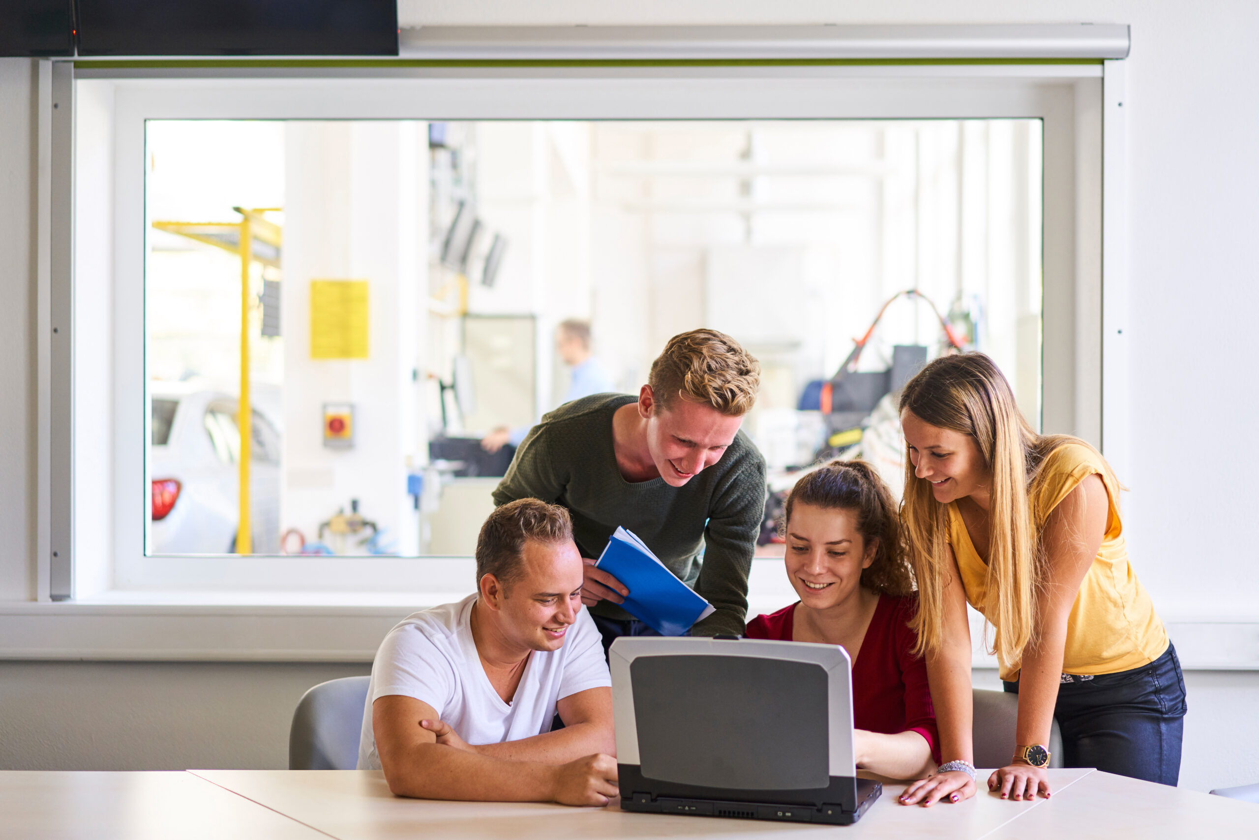 Eine Gruppe Studentinnen und Studenten sitzen vor einem Laptop.