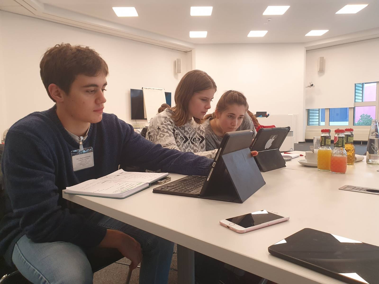 Eine Gruppe Schülerinnen und Schüler sitzen vor Tablets.