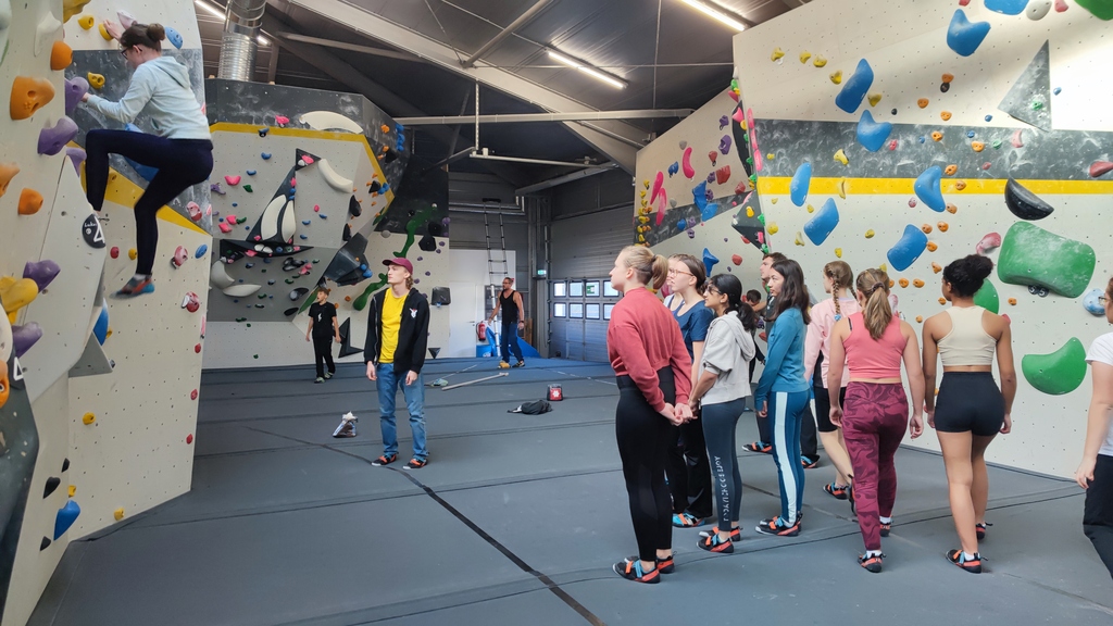 Eine Gruppe Schülerinnen vor einer Kletterwand.