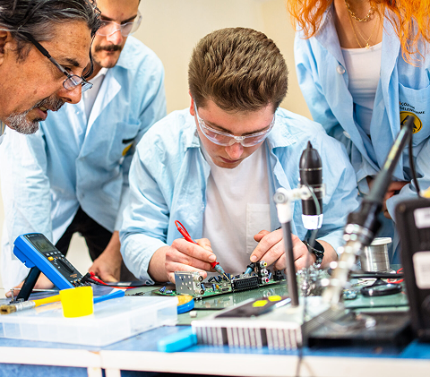 Schülerinnen und Schüler löten eine Halbleiterplatine.
